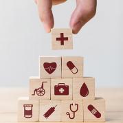 Wooden blocks, decorated with various medical symbols, being stacked by a person's hand