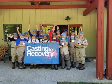 Group of people waving while holding a Casting for Recovery banner