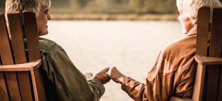 Two people sitting near water and holding hands