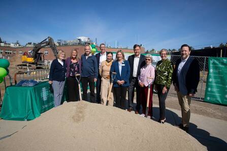 A group of people stand in a line in front of a construction site.